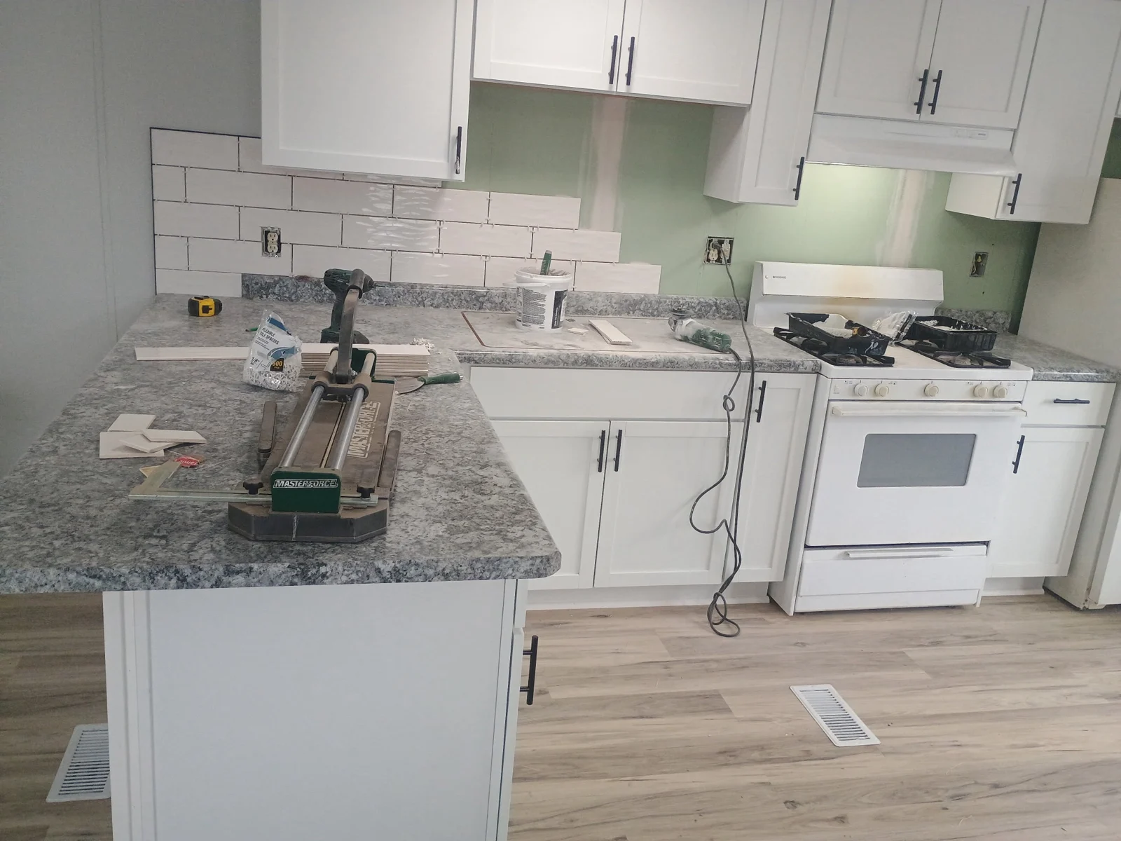 Kitchen remodeling with seams taped and mudded before backsplash installation. The backsplash is underway.